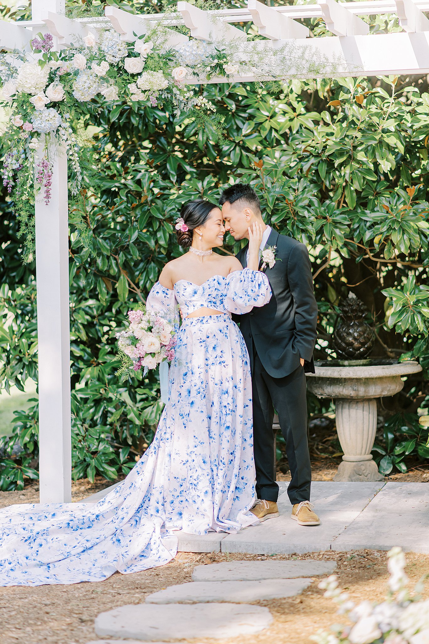 Newlyweds stand under their ceremony arbor in a blue gown and black suit