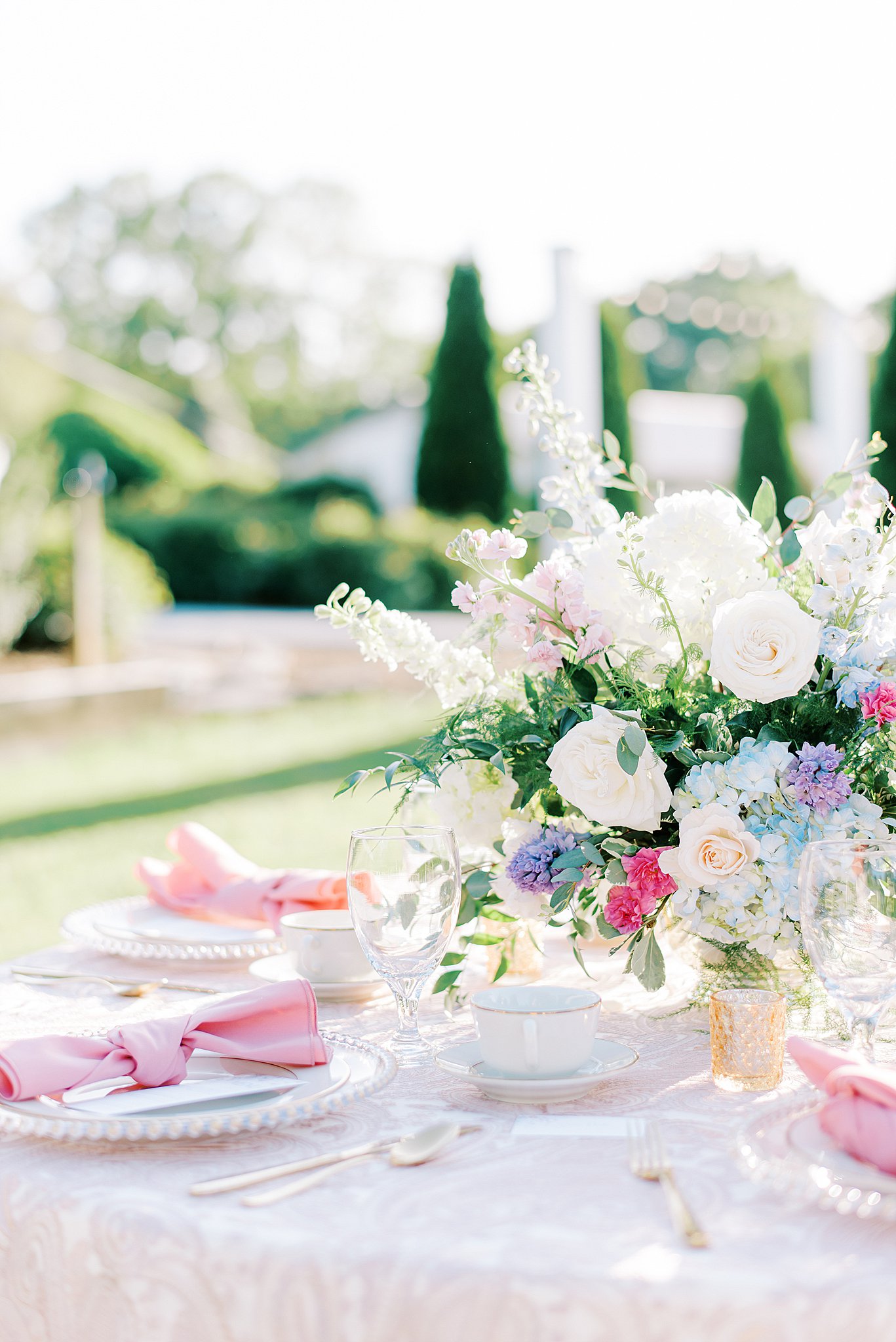 Details of an outdoor wedding reception table complete with flowers and pink linens