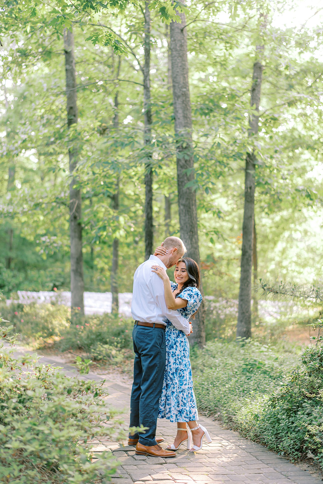 Newlyweds stand in a stone path through a garden hugging under trees Morning Glory Farm