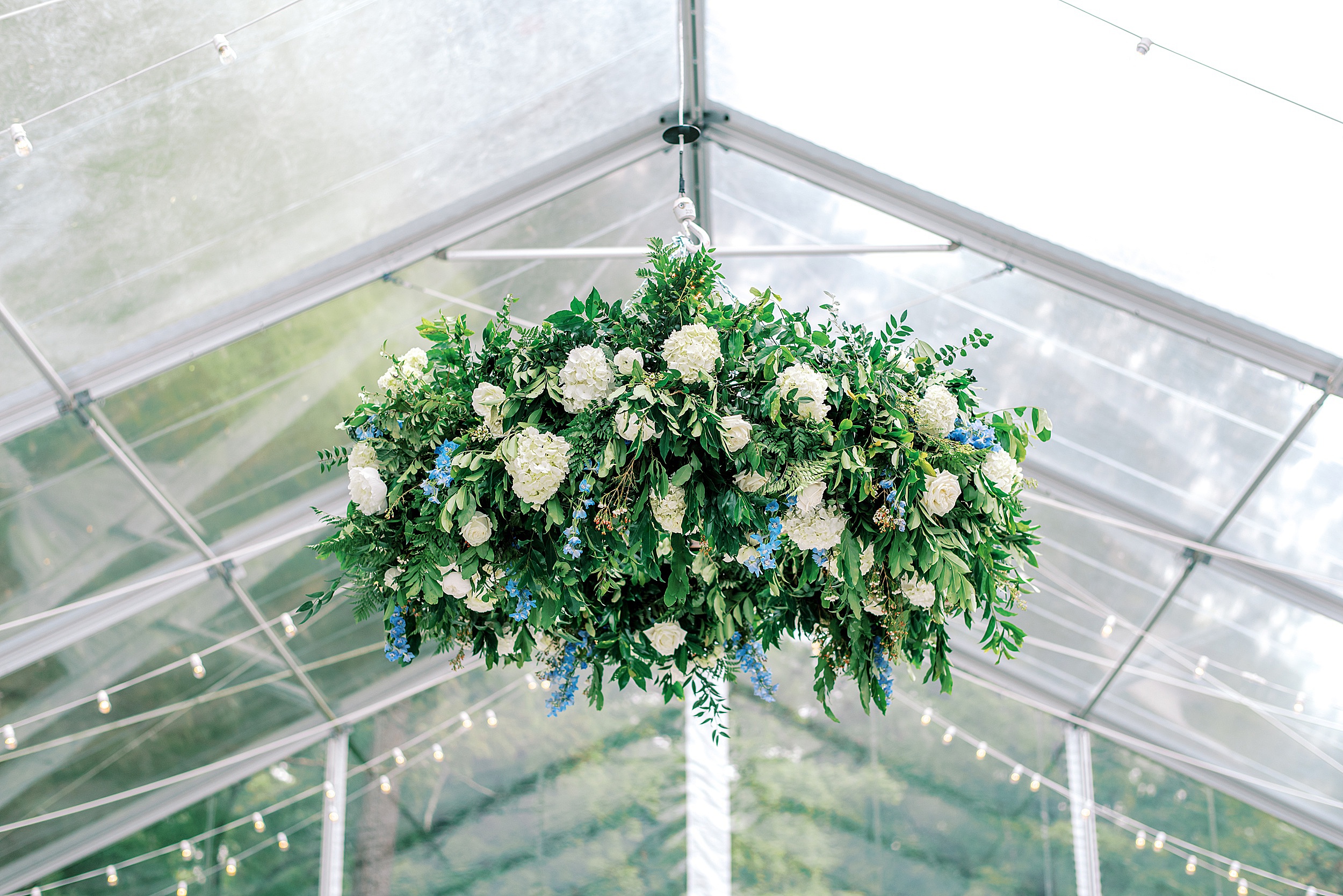 Details of a hanging wedding floral arrangement with white and blue flowers at one of the
